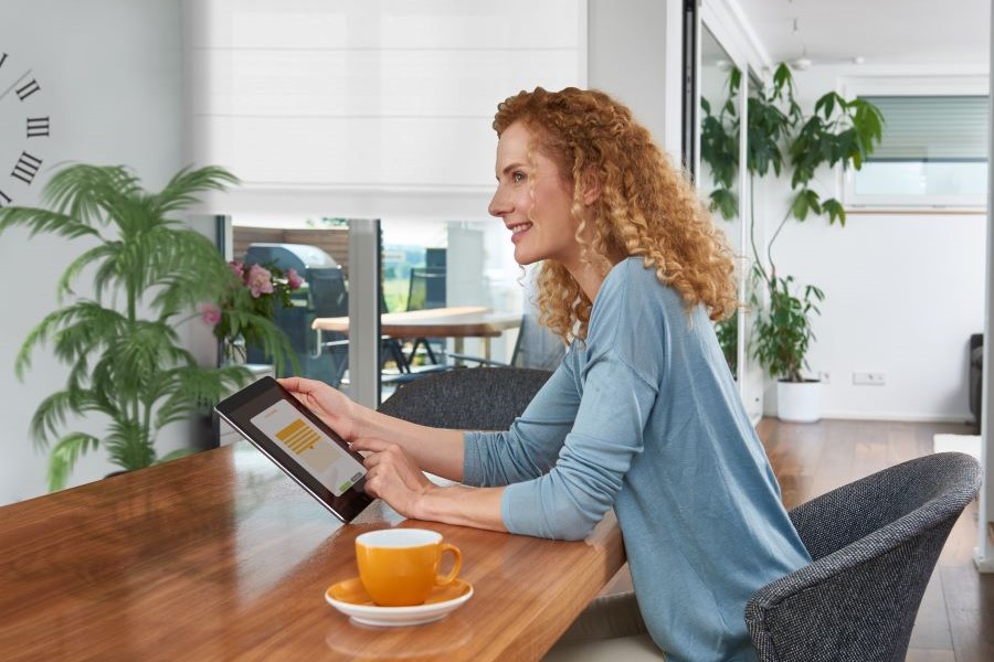 Frau steuert ihr Smart Home über ein Tablet